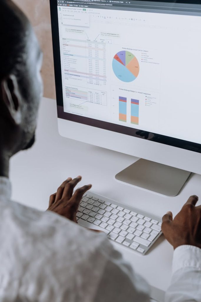 Businessman analyzing charts and data on desktop computer in office setting.